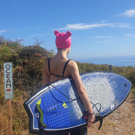 Hot pink swimcap with two buns worn by surfer girl